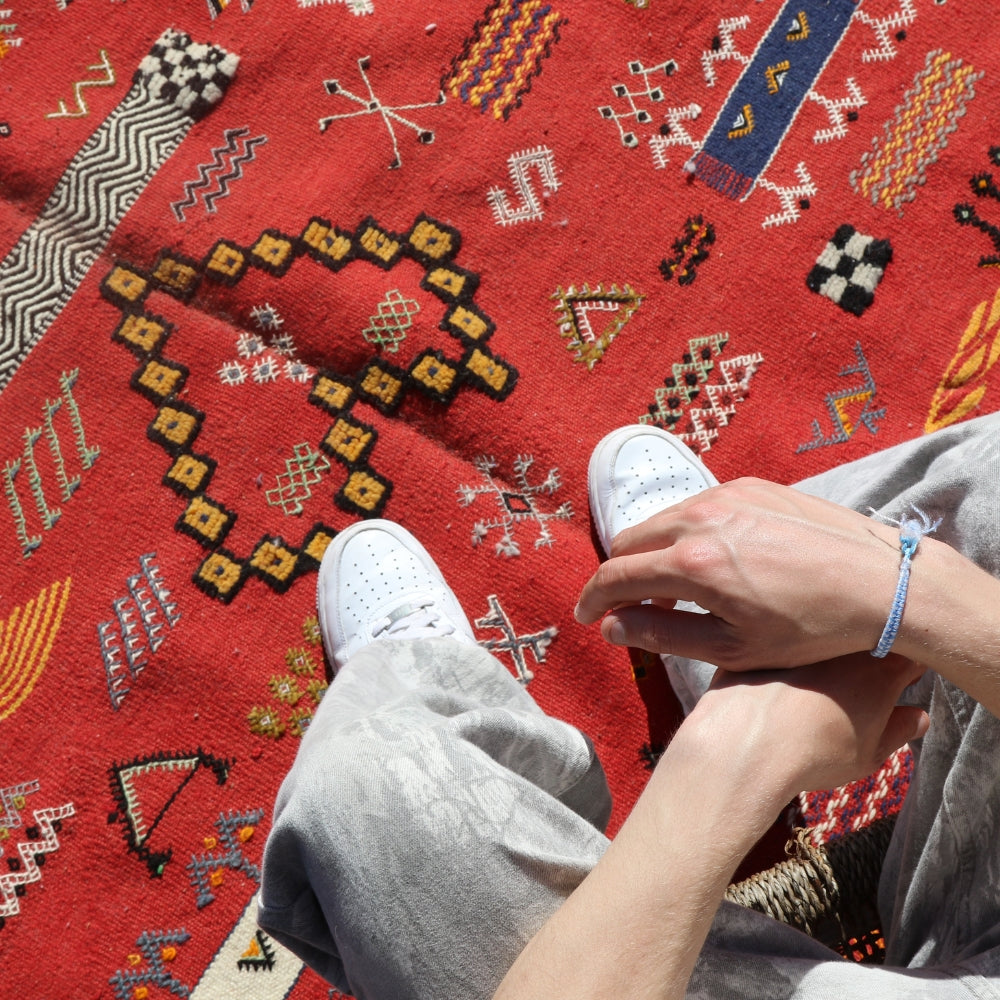 Textured surface of red Aknif flatwoven rug with traditional symbols