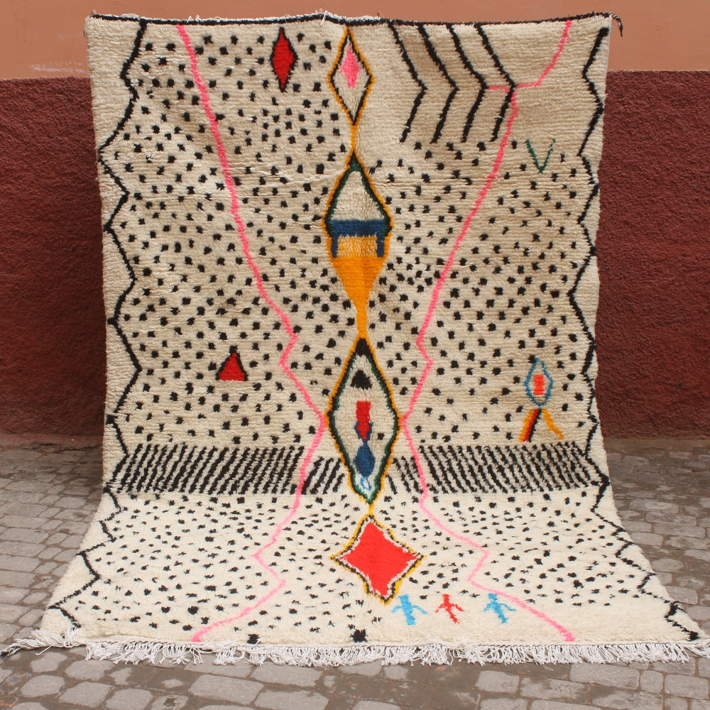 Decorative rug with geometric pattern on a stone floor against a red wall