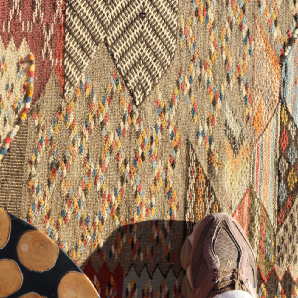 Close-up of handwoven Moroccan Taznakht rug showcasing earthy geometric Berber textile details