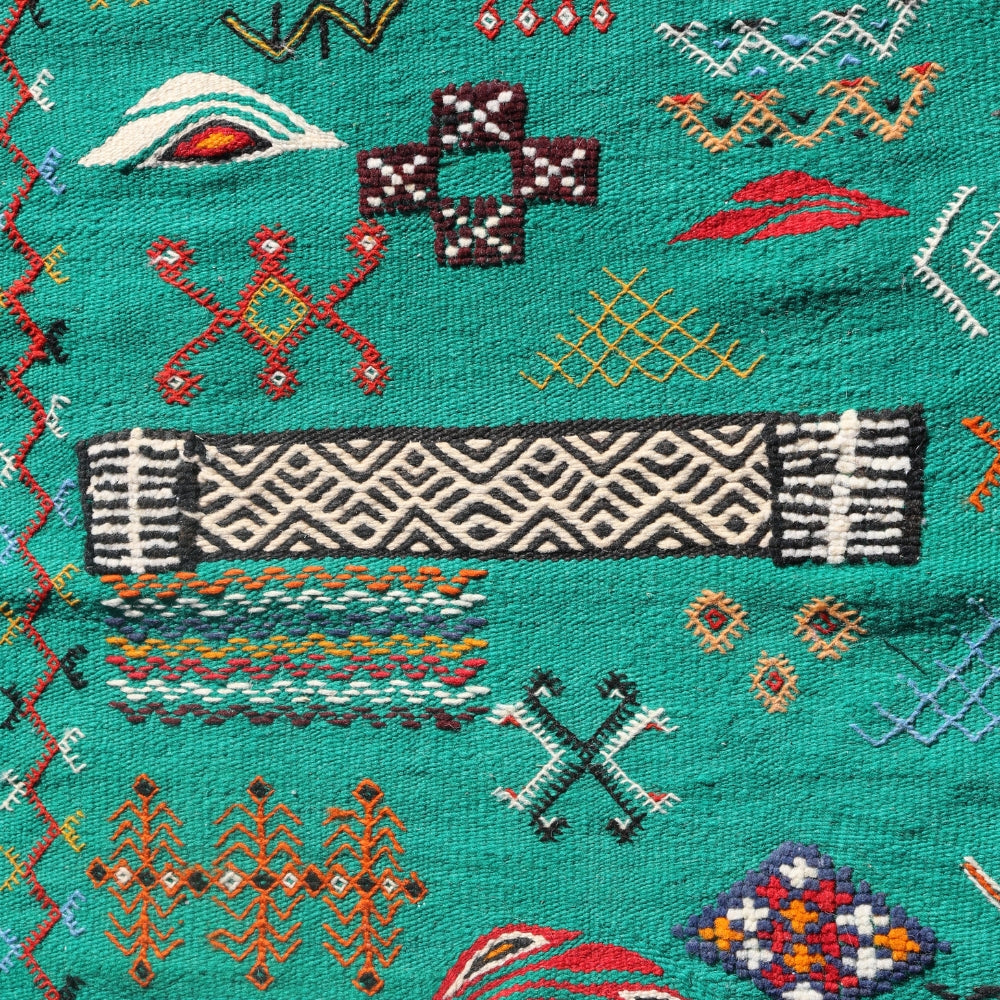 Close up of embroidered Berber motifs on green Aknif wool rug