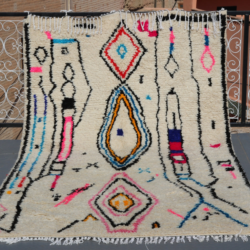 Contemporary Azilal rug handwoven in Morocco, ivory wool with bold abstract berber motifs in pink, blue, yellow, and black