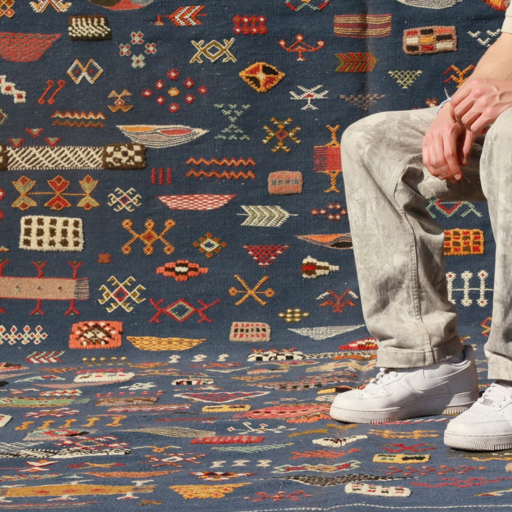 Detail of hand embroidered motifs on blue Aknif flatweave rug, showcasing traditional Berber craftsmanship