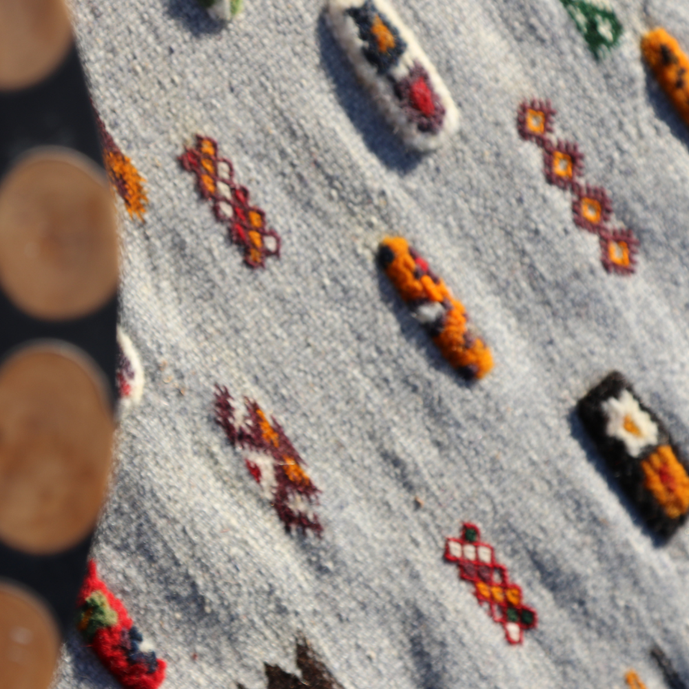Detailed texture of tribal Akhnif wool rug featuring colorful handcrafted Berber embroidery