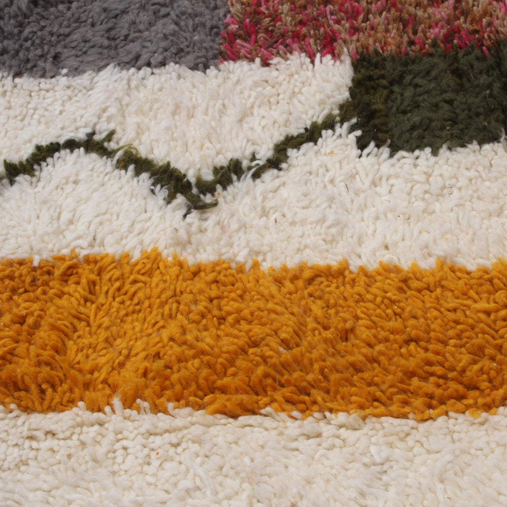 Close-up of a multicolored striped colorful wool boujaad rug with white, orange, green, and gray stripes.